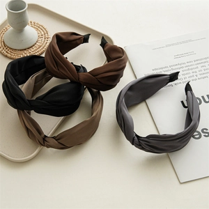 Detail of twisted fabric headbands in assorted earth tones displayed on a chic white tray