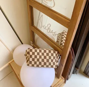 Detail shot of brown checkered knit pouch with metal zipper in aesthetic setting