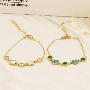 Gold clover bracelets with mother of pearl and green malachite inlays on white silk