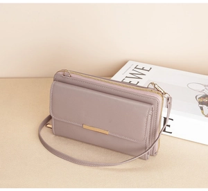 Detail of mauve leather crossbody phone bag with gold metal hardware and zipper
