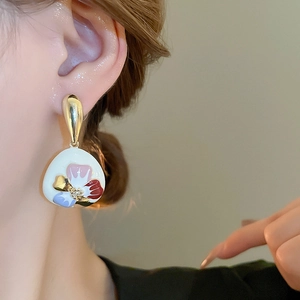 Detailansicht der Emaille-Ohrringe mit Blumenmuster und Goldhaken am Modell