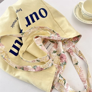 Detail view of canvas tote bag with floral lining and artistic enjoy our music print