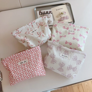 Detailed top view of four fabric makeup bags with various floral and bow patterns