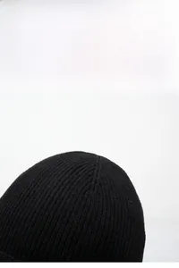 Close-up of black ribbed knit beanie showing thick thermal fabric texture and elastic weave