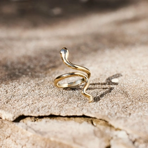 Minimalist gold snake wrap ring in s925 sterling silver on a textured stone background