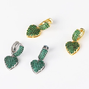 Detail of heart-shaped earrings with micro-set green cubic zirconia in gold and silver