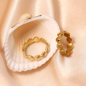 Détail de bagues coquillages plaquées or 18K sur soie rose pour un style luxueux