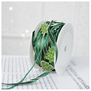 Macro shot of dark green Christmas ribbon with gold trim and festive pine tree accents