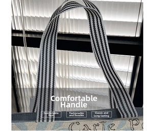 Close-up of reinforced striped woven handles and blue jacquard texture on canvas tote bag