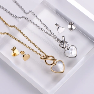 Macro detail of heart pendant necklace and earrings set with iridescent shell inlay