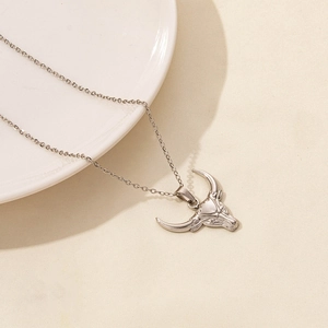 Close-up of silver stainless steel bull head pendant on a fine link chain necklace