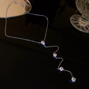 Silver Y-shaped drop necklace with four pear-cut zircons on a reflective black base