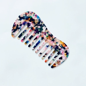 Detailed close-up of marble acetate wide-tooth comb with colorful tortoiseshell pattern