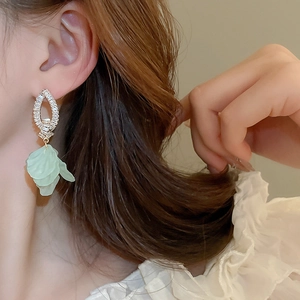Close-up of model wearing green floral drop earrings with sparkling zircon crystals
