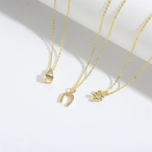 Detailed view of three gold necklaces featuring teardrop, horseshoe, and flower pendants