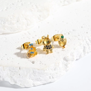 Detail of gold astronaut and spaceship earrings with inlaid blue and green zircon