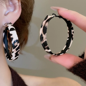 Close-up of vintage leopard print leather-wrapped C-shaped hoop earrings on a model