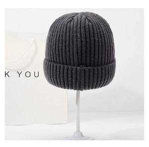 Détail du bonnet en tricot gris foncé à côtes avec revers présenté sur un support blanc