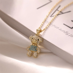 Close-up of a gold-plated bear pendant necklace with sparkling blue and clear crystals