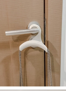 Detail van witte plastic kast haak met een zilveren ketting aan de deur bevestigd