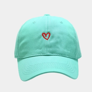 Detail shot of a mint green cotton baseball cap with a small red heart embroidery