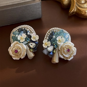 Detail of vintage flower stud earrings featuring pearls, blue resin, and crystal accents