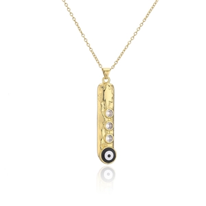 Detail of gold geometric bar pendant with star texture and black evil eye enamel inlay