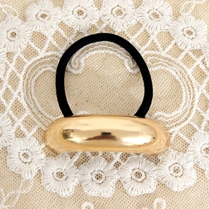 Close-up of minimalist hair tie with polished gold metal bead and black elastic band
