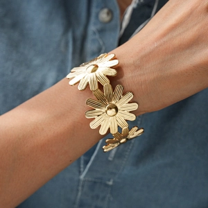 Vue détaillée d'un bracelet manchette fleur de marguerite dorée sur fond de jean