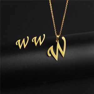 Detail of gold cursive letter W pendant necklace and matching stud earrings set