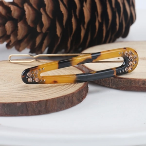 Elegant oval acetate hair clip with tortoiseshell texture and amber rhinestones