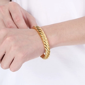 Gros plan d'un bracelet jonc torsadé en acier titane doré 18k porté au poignet