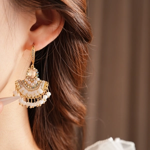 Gros plan de boucles d'oreilles vintage en éventail avec gemmes et pompons de perles