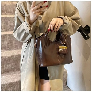 Detail of dark brown vintage oil wax leather tote with metal chain and charm