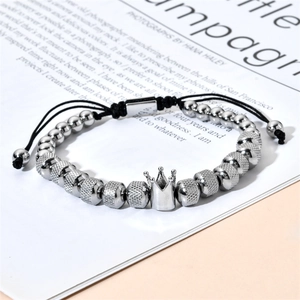 Macro detail of silver beads and crown charm on a black braided cord bracelet