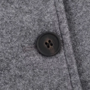 Detail of grey wool coat showing high-quality fabric texture and black four-hole button