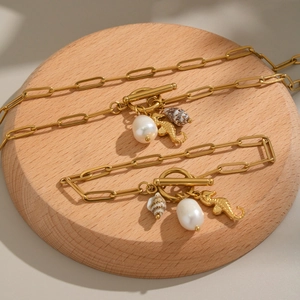 Detail of 18K gold paperclip necklaces with baroque pearl and seahorse pendants