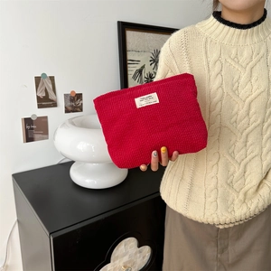 Macro detail of red corduroy makeup bag texture with decorative woven label