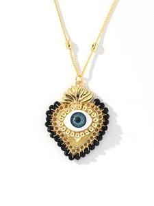 Detailed view of 18k gold heart pendant with a blue evil eye and black bead chain