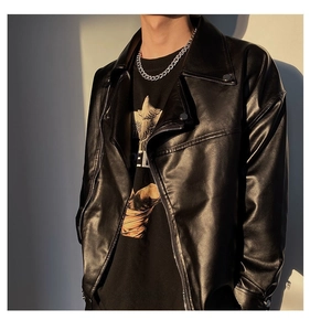 Détail d'un collier à grosse chaîne cubaine argentée porté avec une veste en cuir noir