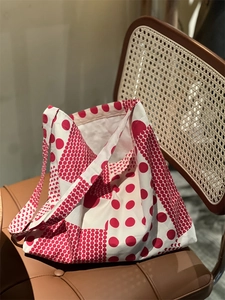 Détail du sac cabas en toile à pois rouges et blancs posé sur une chaise en cuir rétro