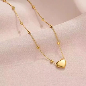 Elegant gold titanium steel heart pendant necklace on soft pink silk background