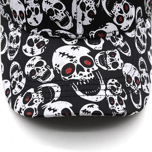 Macro detail of red-eyed skull print and reinforced stitching on black cotton baseball cap