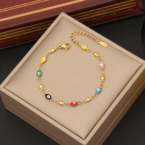 Gold-plated evil eye charm bracelet with multicolored enamel pendants on jewelry box