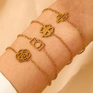 Close-up of gold-plated bracelets featuring cactus, clover, and camera charms