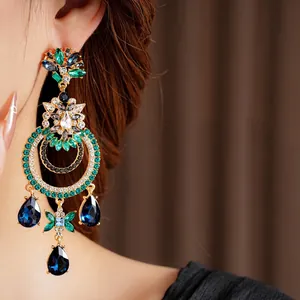 Vintage gold drop earrings with blue waterdrop gems and diamonds worn by a model