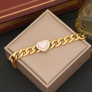 Detailed view of a gold chain bracelet with a heart pendant and white shell inlay