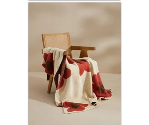 Detailed knit texture of sunflower throw blanket with soft red and cream floral patterns