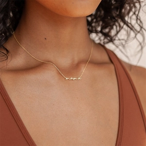 Golden mama letter pendant necklace on minimalist chain worn by female model in casual setting