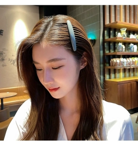 Close-up of a light blue matte hair comb clip worn by a model in a cafe setting